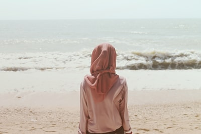 女人坐在沙滩岸边的海浪
